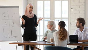 Eine Frau steht vor einer Businessgruppe und präsentiert ihre Ideen.