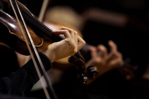 Eine Geigerin spielt auf ihrem Instrument. Im Hintergrund ist eine weitere Geige zu sehen. Bühnenangst und Auftrittsangst kann überwunden werden. Entspanntes Musizieren ist möglich.