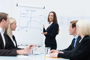 Eine Frau steht vor einer Businessgruppe und präsentiert ihre Ideen.