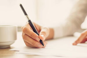 Eine Hand schreibt mit einem Stift auf einem Blatt Papier. Es fühlt sich so gut an, gut auf die Prüfung vorbereitet zu sein und keine Ängste zu haben.