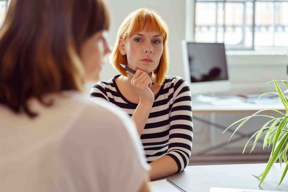 Junge Frau wirkt unglücklich im Job und nachdenklich im Büro – Symbolbild für Unzufriedenheit am Arbeitsplatz ohne Alternative